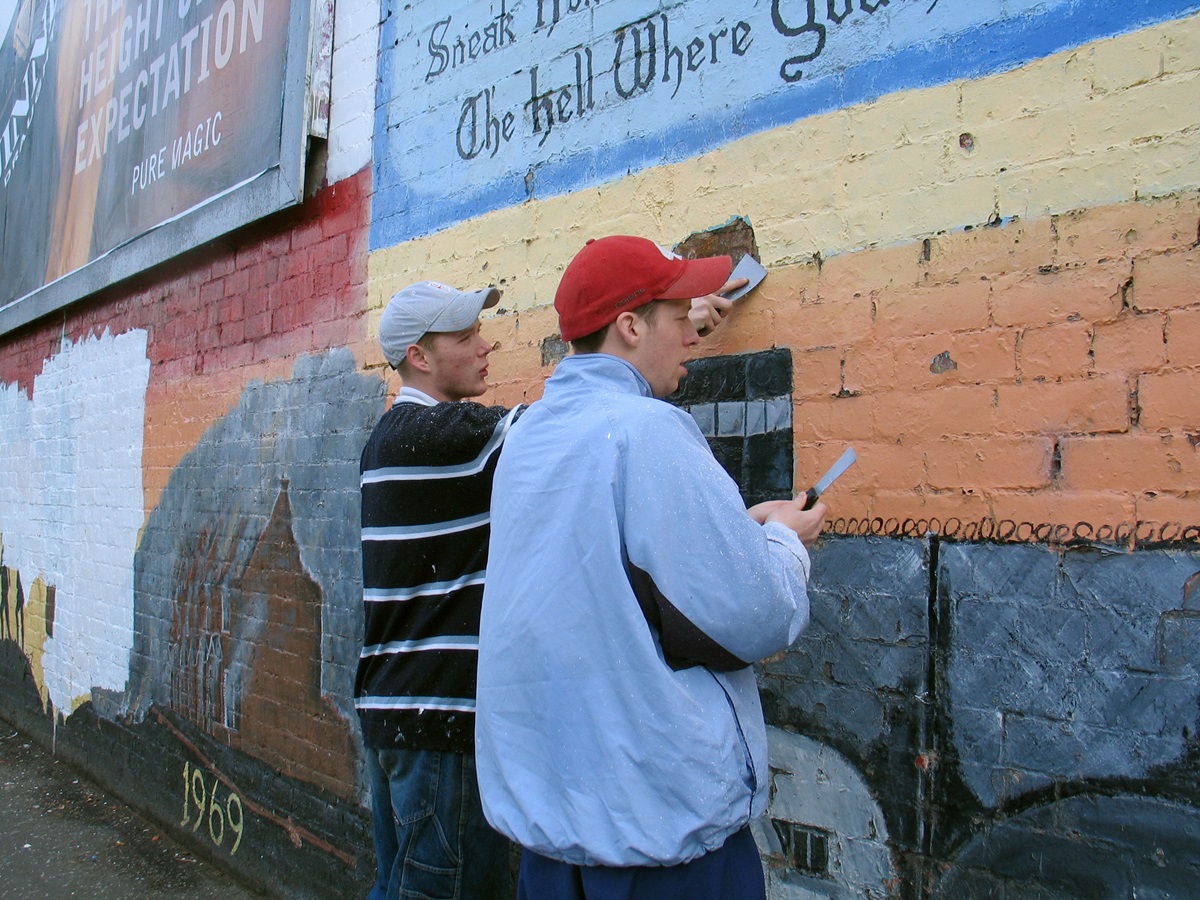 Volunteers remove a traditional paramilitary mural from a wall in in Belfast, Northern Ireland, in 2003 to make way for a new mural that will honor both Catholic and Protestant heroes from the two World Wars. “Brexit” — Britain’s process of withdrawing from the 28-member European Union — is raising concerns about re-imposing hard borders on the island of Ireland. File photo by Kathleen LaCamera.  Volunteers remove a traditional paramilitary mural from a wall in in Belfast, Northern Ireland, in 2003 to make way for a new mural that will honor both Catholic and Protestant heroes from the two World Wars. “Brexit” — Britain’s process of withdrawing from the 28-member European Union — is raising concerns about re-imposing hard borders on the island of Ireland. File photo by Kathleen LaCamera.