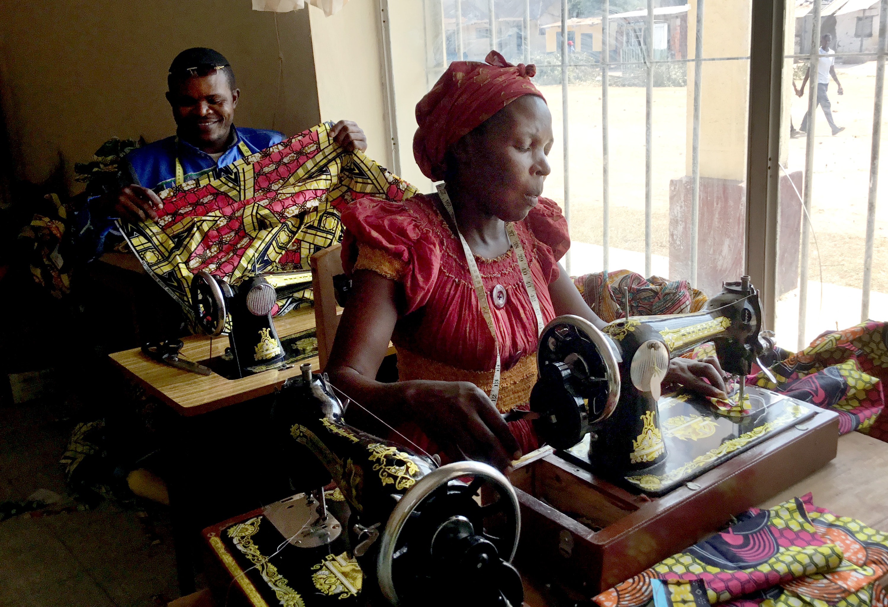 A student at the United Methodist sewing center in Kamina, Congo, practices what she has learned from teacher Ilunga Nday Lebon (rear). Until recently, clerical shirts, United Methodist Women blouses and altar cloths were ordered from Lubumbashi, 370 miles from Kamina. Today, the items are sewn locally, saving time and money. Photo by Betty Kazadi Musau, UM News.