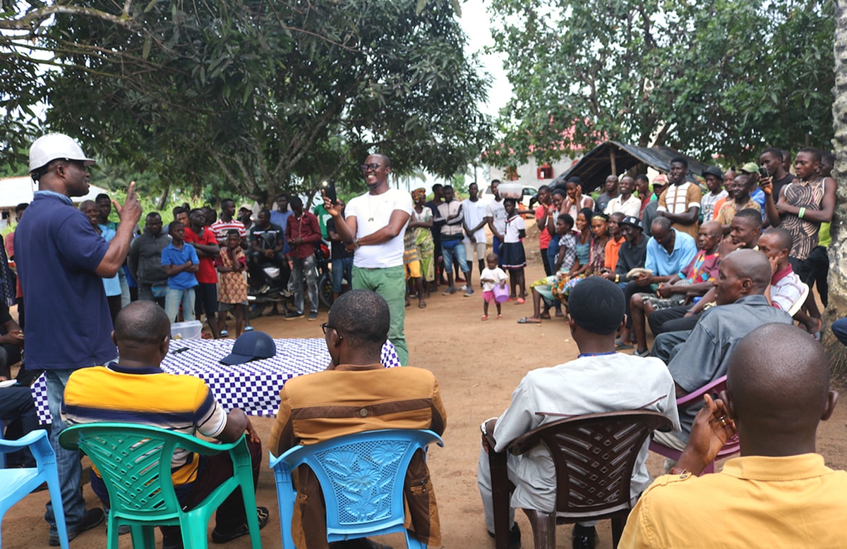 The Sierra Leone Minister of Lands, Housing and Environment, Denis Sandy (left in helmet), explains to the Masantigie community details of the agreement signed between the community and the Sierra Leone Conference regarding the disputed Pa Loko property. Photo by Phileas Jusu, UM News.