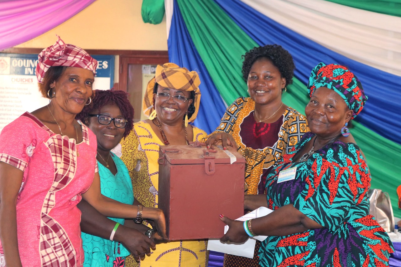 United Methodist Women regional missionaries Elmira Sellu (third from left) and Finda Quiwa (fourth from left) hold a lock box that is part of a new loan program for women during a four-day training in Freetown, Sierra Leone. The microfinance project, funded by United Methodist Women, is one of two empowerment programs the Regional Missionary initiative launched in September. Photo by Phileas Jusu, UM News.
