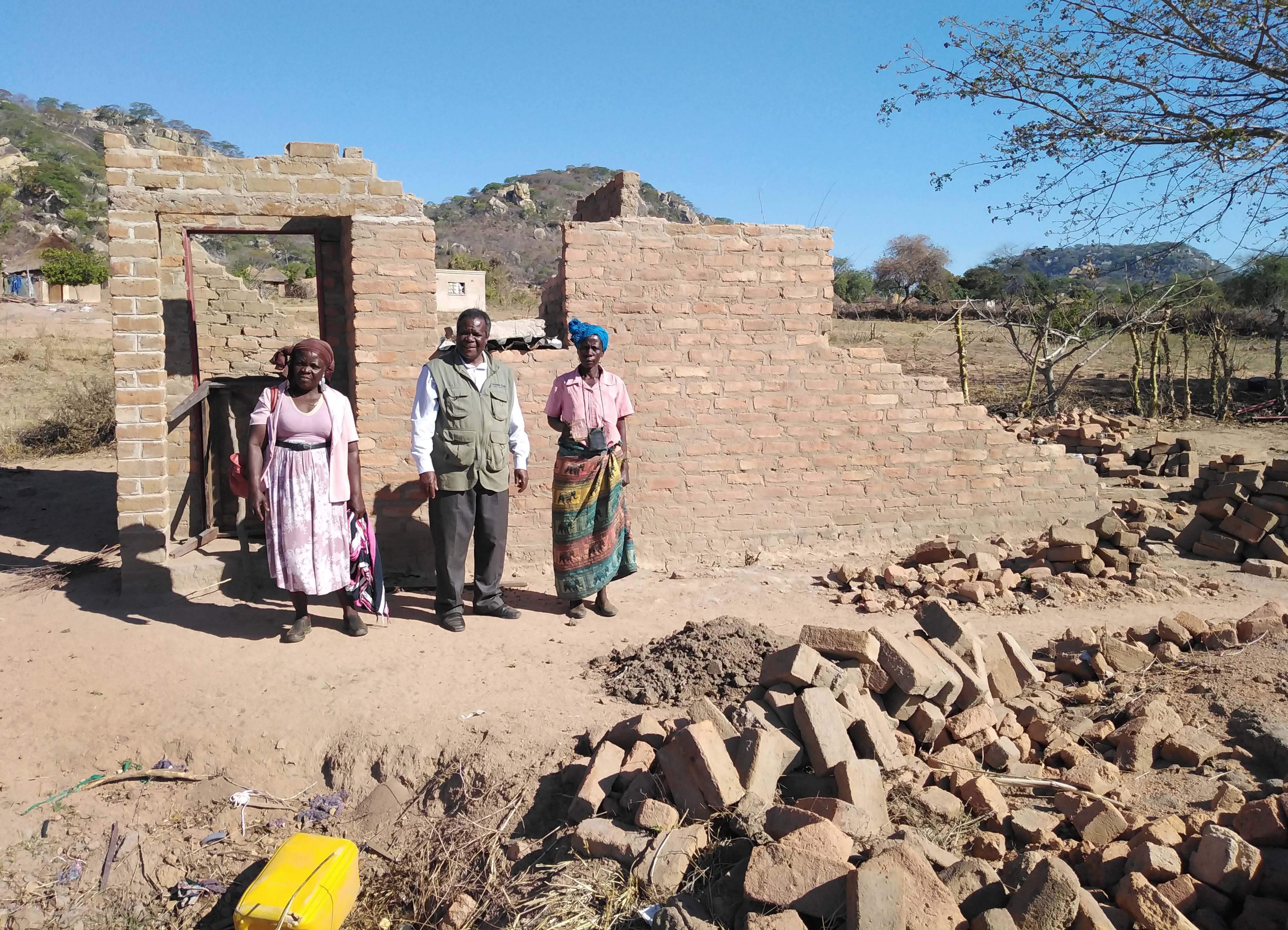 Vivian Chigweshe, à droite, se tient devant sa maison, qui a été détruite par le cyclone Idai en mars. Elle est l’une des survivants qui grâce au soutien de l'Église Méthodiste Unie se feront construire une nouvelle maison. (A partir de la gauche sur la photo), le leader laïc Chirobwe Kupeti et le révérend Jairos Mafondokoto, surintendant du district de Masvingo. Photo de Chenayi Kumuterera, UM News.