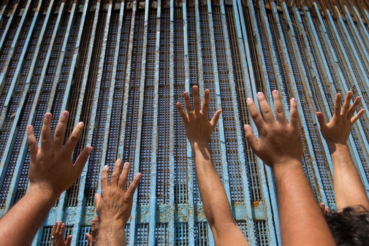 Parishioners of the Border Church in Tijuana, Mexico, lift their arms skyward beneath the  fence that marks the border with the U.S. The Methodist Church of Mexico and The United Methodist Church in the U.S. share communion each Sunday across the fence.