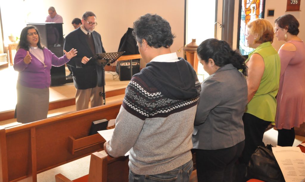 La Revda. Lucky Cotto (a la izquierda con las manos en alto) bendice a la congregación satélite de Casa del Pueblo en la IMU San Pablo, en Warrington, Pensilvania. Foto Jhon Coleman. 