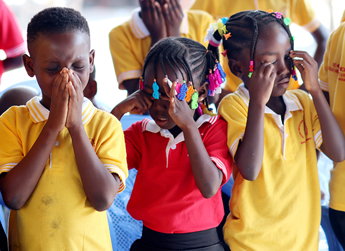 (From left) Eunice Mel, 9, Syntiche Tia, 5, and Gnonsio Tryphene, 9, members of Bethel United Methodist Church at Ampain Ivorian Refugee Camp in Ampain, Ghana, pray during a Christmas Day celebration at the camp. The Aboisso District of The United Methodist Church in Côte d’Ivoire supports the church. Photo by Isaac Broune, UM News.