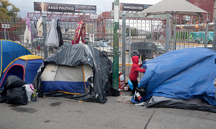 A young boy arranges a tarp to protect his family's tent from rain at a makeshift encampment in Juárez, Mexico, for people waiting to make asylum claims in the U.S. in November 2019. File photo by Mike DuBose, UM News.