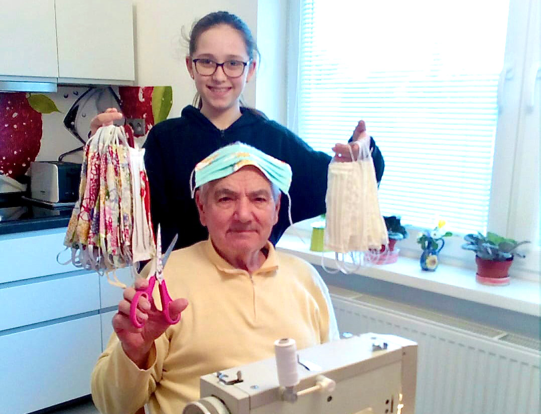 Michal Tagaj, 82, is a member of the United Methodist Church in Sered, Slovakia, and has made more than 80 masks with his sewing machine.  His granddaughter Emma shows off some of the masks, which are being distributed to church members and people in high-risk groups in several different towns. Photo courtesy of the Central Conference of Central and Southern Europe.