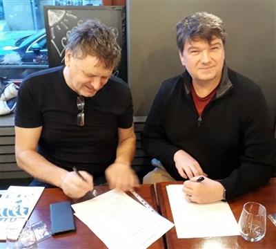 Hicks firmando un contrato con Miroslav Pycha, gerente de la radio. Foto cortesía de la Conferencia Anual de Holston.