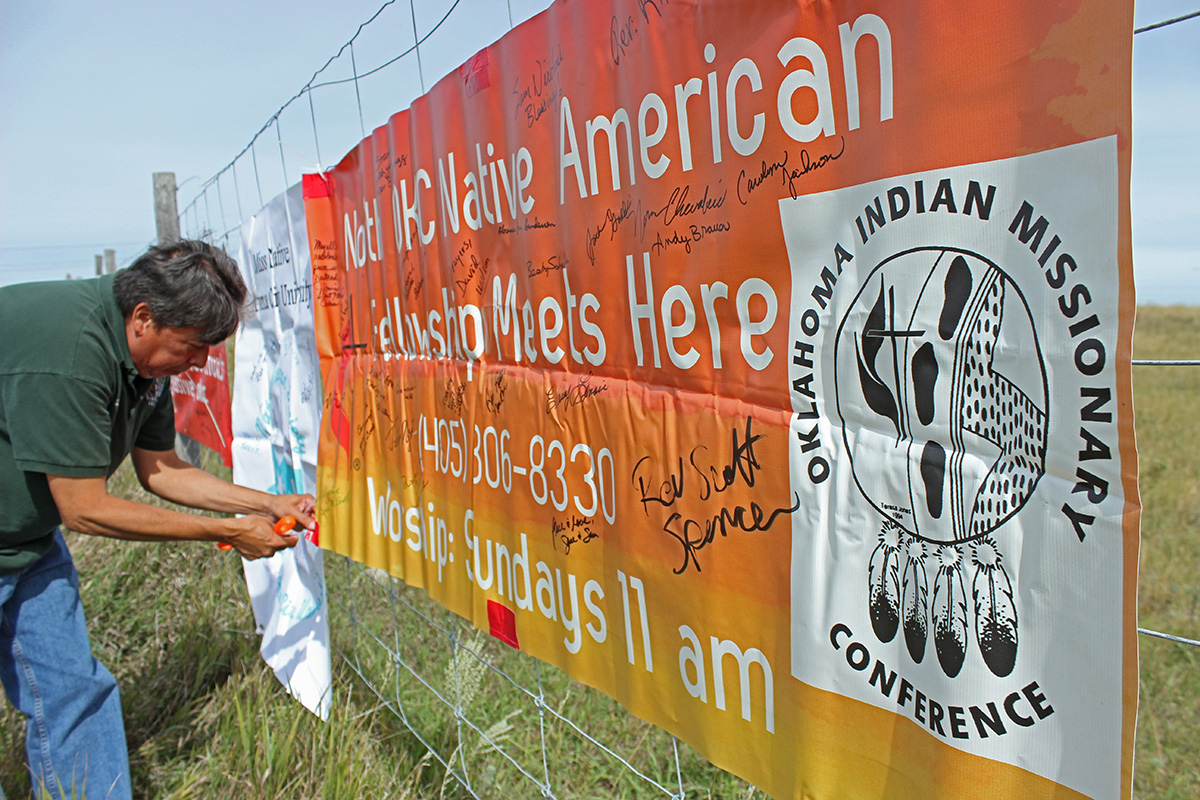 The Rev. David Wilson, conference superintendent of the Oklahoma Indian Missionary Conference of the United Methodist Church, attaches banners from his conference to a fence near the Dakotas Access Pipeline, Highway 1806, near Cannon Ball, N.D. File photo by Dave Stucke, Dakotas Conference. The Rev. David Wilson, conference superintendent of the Oklahoma Indian Missionary Conference of the United Methodist Church, attaches banners from his conference to a fence near the Dakotas Access Pipeline, Highway 1806, near Cannon Ball, N.D. File photo by Dave Stucke, Dakotas Conference.