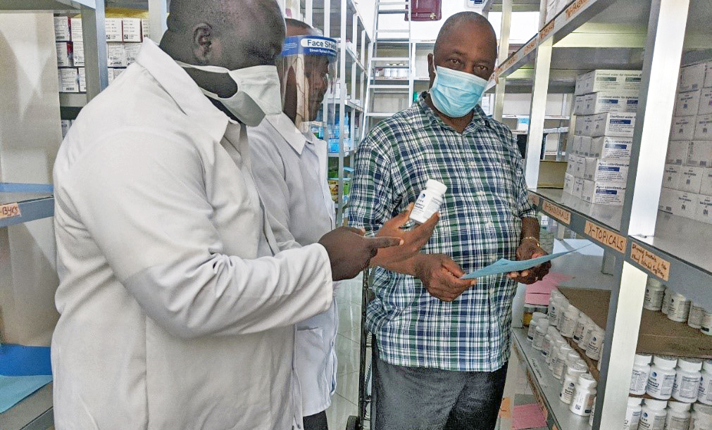 Allen S.D. Zomonway (right), a registered nurse and Ganta United Methodist Hospital administrator, reviews drug stocks with staff in the hospital pharmacy. During the pandemic, the Africa University graduate ensures that all hospital employees wear masks and take other necessary precautions. Photo courtesy of Africa University. Allen S.D. Zomonway (right), a registered nurse and Ganta United Methodist Hospital administrator, reviews drug stocks with staff in the hospital pharmacy. During the pandemic, the Africa University graduate ensures that all hospital employees wear masks and take other necessary precautions. Photo courtesy of Africa University.