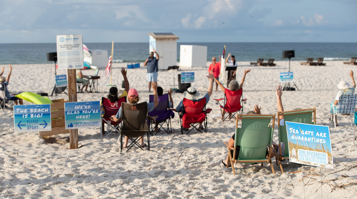 Worshippers raise their arms in praise during the Galilean Beach Service, a ministry of Foley (Ala.) United Methodist Church at Gulf State Park in Gulf Shores, Ala. 