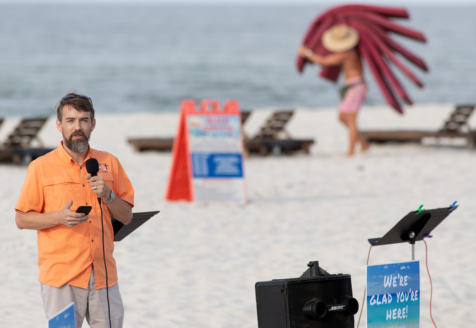 The Rev. Nolan Donald gives the sermon during the Galilean Beach Service while a beach attendant lays out chair cushions in the background. The 7:30 a.m. service is over before most other beachgoers arrive. Photo by Mike DuBose, UM News.