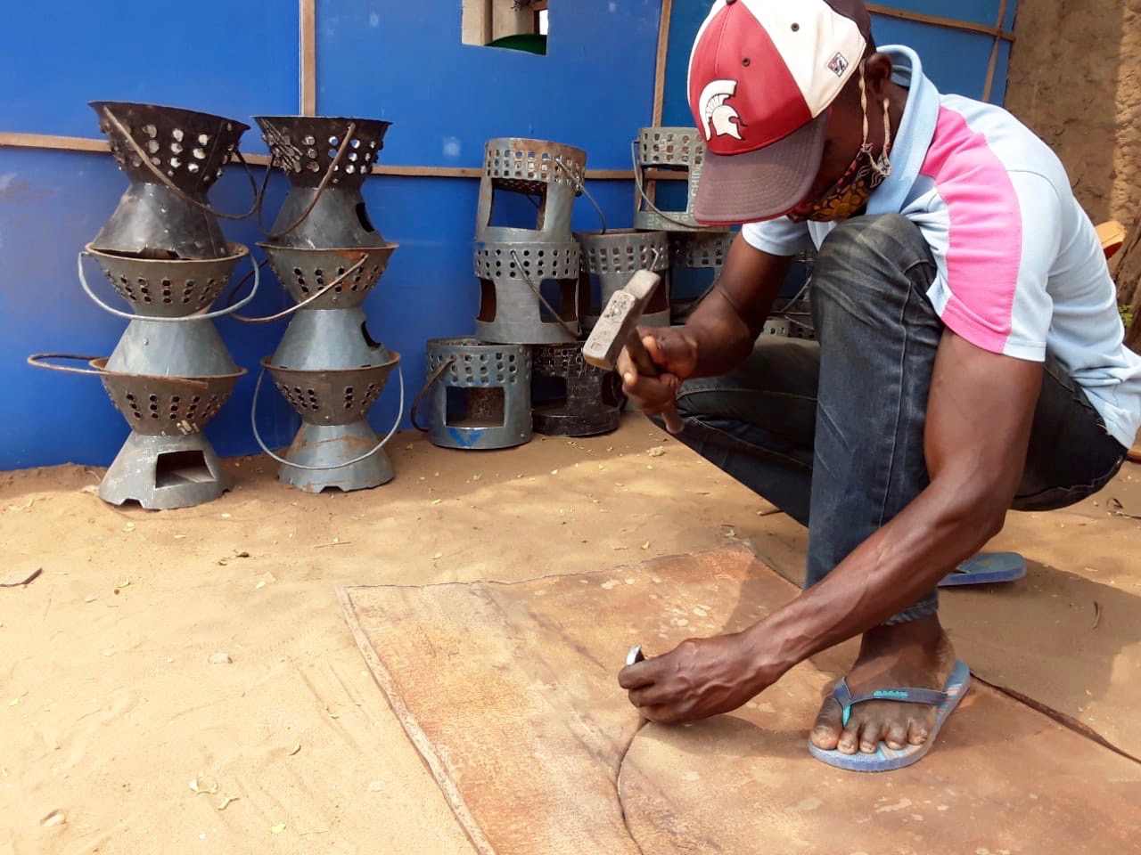 Mestre Mbala trabalha uma chapa reciclada fazendo o contorno para a produção de fogão em Luanda, Angola. Foto de Augusto Bento.