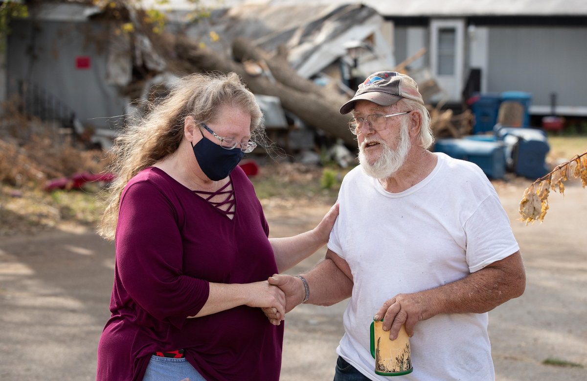 The Rev. Catie Newman prays with John W. Weaver in front of a neighbor’s wind-damaged home while a United Methodist volunteer team makes emergency repairs to his roof in Marion, Iowa. Weaver’s mobile home was severely damaged during a derecho windstorm Aug. 10. Newman is the disaster response coordinator for the Iowa Conference.  The Rev. Catie Newman prays with John W. Weaver in front of a neighbor’s wind-damaged home while a United Methodist volunteer team makes emergency repairs to his roof in Marion, Iowa. Weaver’s mobile home was severely damaged during a derecho windstorm Aug. 10. Newman is the disaster response coordinator for the Iowa Conference.