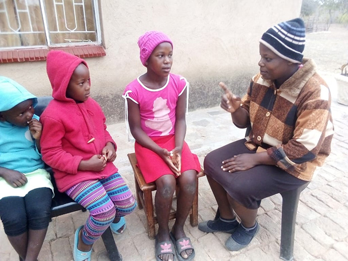 Perpetual Makadzange talks to her three children, (from left) 6-year-old Tizzy, 7-year-old Tanatswa and 12-year-old Tsepang, at their home in the Chimanimani, Zimbabwe. The United Methodist schools that the children attend remain closed to stop the spread of the coronavirus. Photo by Kudzai Chingwe, UM News. 