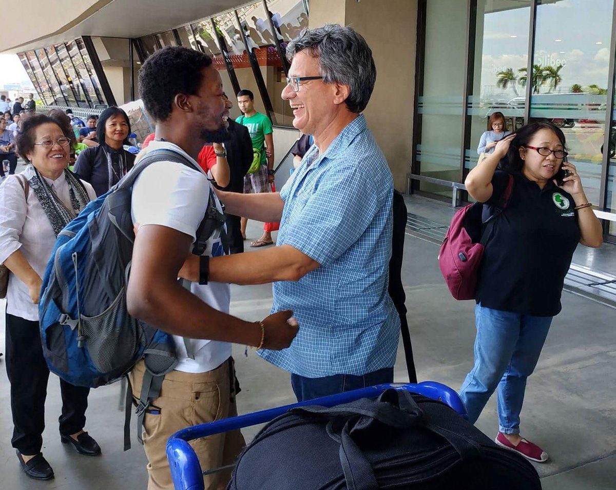 United Methodist missionary Tawanda Chandiwana (left foreground) is embraced by Thomas Kemper, head of the Board of Global Ministries, at the Ninoy Aquino International Airport in Manila, Philippines, on July 1, 2018, after Chandiwana was released from a detention center and allowed to leave the country. 2018 file photo courtesy of Thomas Kemper, Global Ministries. United Methodist missionary Tawanda Chandiwana (left foreground) is embraced by Thomas Kemper, head of the Board of Global Ministries, at the Ninoy Aquino International Airport in Manila, Philippines, on July 1, 2018, after Chandiwana was released from a detention center and allowed to leave the country. 2018 file photo courtesy of Thomas Kemper, Global Ministries.