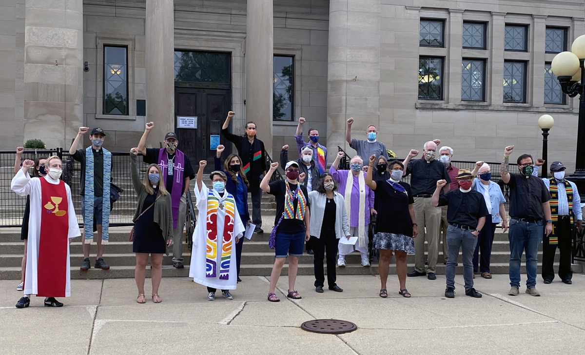 The Rev. Grace Cajiuat (third from left in front row), pastor of Wesley United Methodist Church in Kenosha, Wis., protests with other interfaith religious leaders at Simmons Library Park on Sept. 1, the day President Trump visited the city near Milwaukee. Photo by Chris Herigstad. The Rev. Grace Cajiuat (third from left in front row), pastor of Wesley United Methodist Church in Kenosha, Wis., protests with other interfaith religious leaders at Simmons Library Park on Sept. 1, the day President Trump visited the city near Milwaukee. Photo by Chris Herigstad.