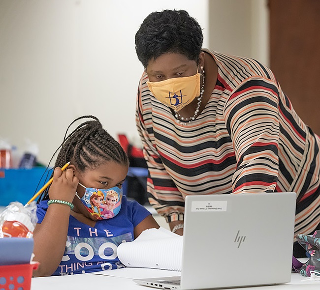 La Revda. Enid Henderson ayuda a una estudiante de primer grado con sus lecciones durante el primer día del programa Santuarios de Aprendizaje en la IMU Jones Memorial en Crestmont Park, Houston. Foto de Mike DuBose, Noticias MU.