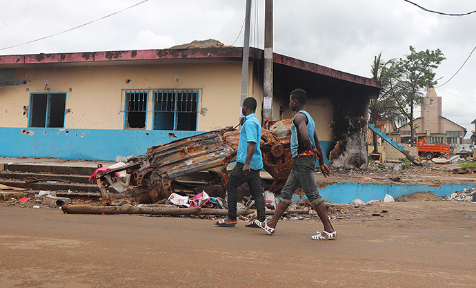 A burned vehicle lies in front of the bullet-riddled police station near Emmanuel United Methodist Church (right, background) in Bonoua, 50 kilometers southeast of Abidjan, Côte d’Ivoire. On Aug. 13, 2020, demonstrators set fire to the building to protest President Alassane Ouattara’s decision to run for a third term against the constitution. An 18-year-old boy was killed by law enforcement according to local authorities. Photo by Isaac Broune, UM News.