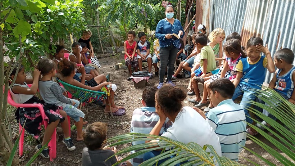 Voluntarios/s de la IMU Casa de Paz en Villanueva, Honduras, atienden a niños/as en el refugio de la iglesia, donde conviven 40 familias de las cuales 8 son miembros de esta congregacion metodista. El Pastor Félix Medina (derecha), junto con voluntarios/as de la IMU Casa de Paz reparten alimentos, donados por miembros de la comunidad, entre familias que han sido afectadas en las áreas vecina a la iglesia. Foto cortesía de la IMU Casa de Paz. 