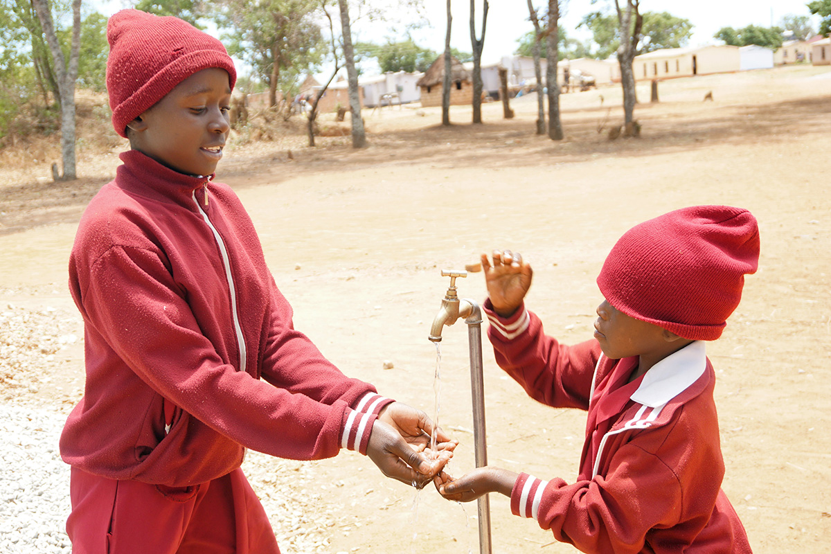 Students Munashe Chidewu (left) and Nyasha Homba wash their hands at a faucet served by a solar-powered well pump at the United Methodist Hanwa Mission in Macheke, Zimbabwe. Photo by Kudzai Chingwe, UM News.