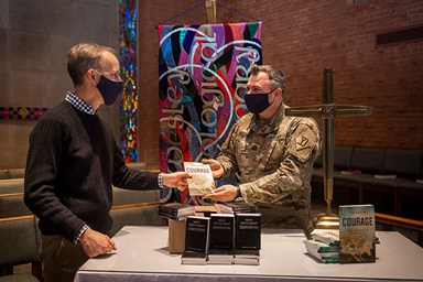 The Rev. Tom Berlin (left) presents a copy of his book, “Courage,” to Massachusetts National Guard Chaplain Chad McCabe in the chapel at Wesley Theological Seminary in Washington. McCabe, whose unit was assigned to help provide security at the U.S. Capitol after the January riot, contacted Wesley Seminary asking for Bibles, novels and board games for troops stationed there. Photo by Lisa Helfert for Wesley Theological Seminary. Copyright 2021. All rights reserved. Used with permission. The Rev. Tom Berlin (left) presents a copy of his book, “Courage,” to Massachusetts National Guard Chaplain Chad McCabe in the chapel at Wesley Theological Seminary in Washington. McCabe, whose unit was assigned to help provide security at the U.S. Capitol after the January riot, contacted Wesley Seminary asking for Bibles, novels and board games for troops stationed there. Photo by Lisa Helfert for Wesley Theological Seminary. Copyright 2021. All rights reserved. Used with permission.