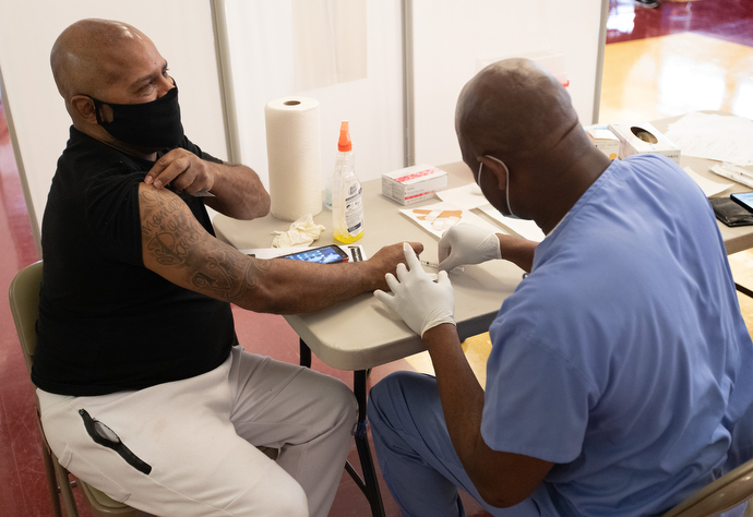 Vincent Richardson rolls up his sleeve to receive a COVID-19 vaccination from Dr. Olayinka Otukpe at Meharry Medical College in Nashville, Tenn. Photo by Mike DuBose, UM News.