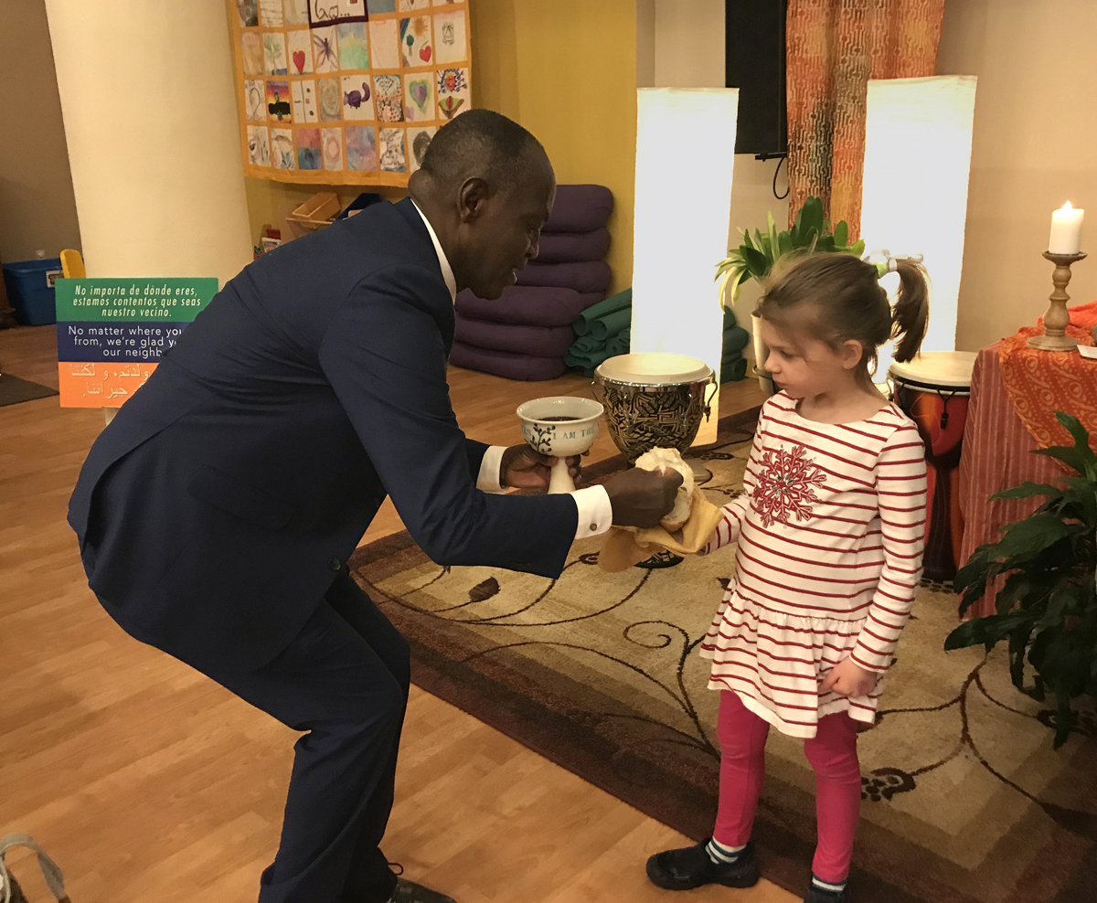 The Rev. Nathan Ndayiziga, a Methodist pastor from Burundi, gives communion to Emilia Lovejoy during a 2019 service at HopeGateWay Church in Portland, Maine. The church is among multiple congregations in the process of disaffiliating from The United Methodist Church. HopeGateWay is doing so in solidarity with LGBTQ members. Photo courtesy of the Rev. Sara Ewing-Merrill. 