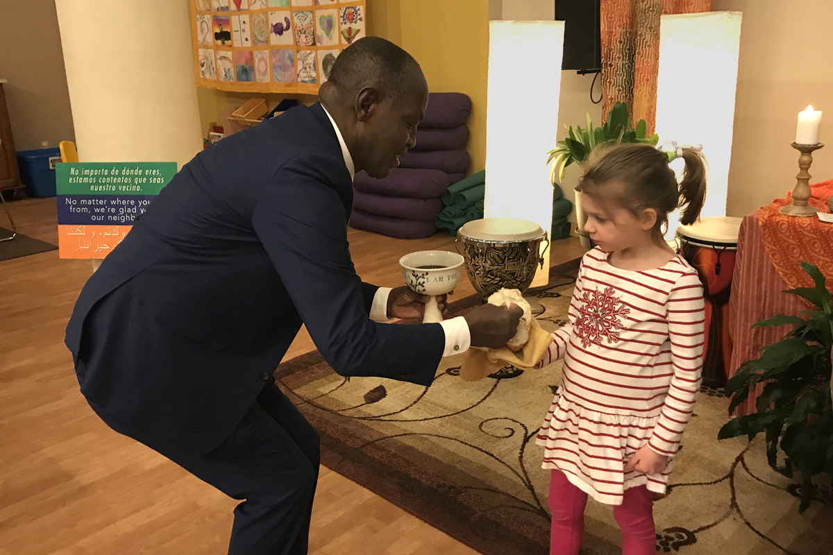El Rev. Nathan Ndayiziga, un pastor metodista de Burundi, administra la comunión a Emilia Lovejoy durante un servicio de 2019 en la iglesia HopeGateWay en Portland, Maine. La iglesia se encuentra entre varias congregaciones en proceso de desafiliarse de La Iglesia Metodista Unida (IMU). HopeGateWay lo hace en solidaridad con los/as miembros LGBTQ. Foto cortesía de la Revda. Sara Ewing-Merrill. El Rev. Nathan Ndayiziga, un pastor metodista de Burundi, administra la comunión a Emilia Lovejoy durante un servicio de 2019 en la iglesia HopeGateWay en Portland, Maine. La iglesia se encuentra entre varias congregaciones en proceso de desafiliarse de La Iglesia Metodista Unida (IMU). HopeGateWay lo hace en solidaridad con los/as miembros LGBTQ. Foto cortesía de la Revda. Sara Ewing-Merrill.