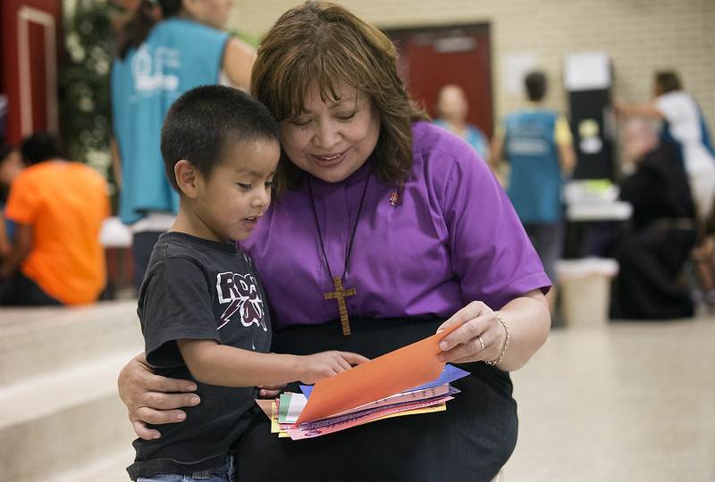 O Bispo Metodista Unido, Minerva Carcaño, compartilha cartas de incentivo com Regino Enrique no centro de boas-vindas a imigrantes na Igreja Católica do Sagrado Coração em McAllen, Texas. O menino de 5 anos e sua mãe, Macaria, chegaram da Guatemala após uma viagem de um mês. Foto de Mike DuBose, Notícias MU.