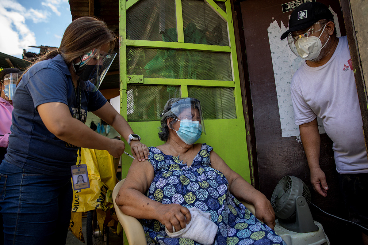 Health workers vaccinate Francia Nolasco, 78, against COVID-19 at her home in Marikina, Metro Manila, Philippines. The United Methodist Board of Church and Society in the Philippines is calling on the government to provide coherent direction in addressing the pandemic crisis. Photo by Eloisa Lopez, Reuters.