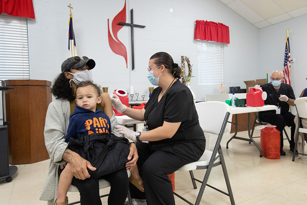 Camisha Henson holds her son Welles in her lap while receiving a COVID-19 vaccination from Tabitha England, RN, during a clinic at St. Mark’s United Methodist Church in Charlotte, N.C.  Camisha Henson holds her son Welles in her lap while receiving a COVID-19 vaccination from Tabitha England, RN, during a clinic at St. Mark’s United Methodist Church in Charlotte, N.C.