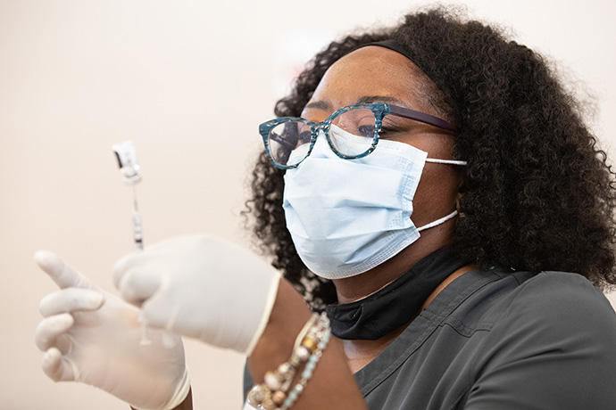 Tia Moore, a nurse practitioner, prepares a dose of COVID-19 vaccine during a vaccination clinic at Meharry Medical College in Nashville, Tenn., in March. The United Methodist-related school has served as a vaccination site since January and also operates a mobile vaccine clinic. File photo by Mike DuBose, UM News.