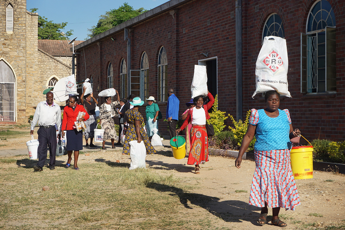 Community members leave with bundles of food and sanitation supplies after a distribution at Murewa Center United Methodist Church outside Harare, Zimbabwe. United Methodist Women, The Nyadire Connection and Harare East District have joined hands to help nearly 800 families struggling with food insecurity during the COVID-19 pandemic. Photo by Kudzai Chingwe, UM News.
