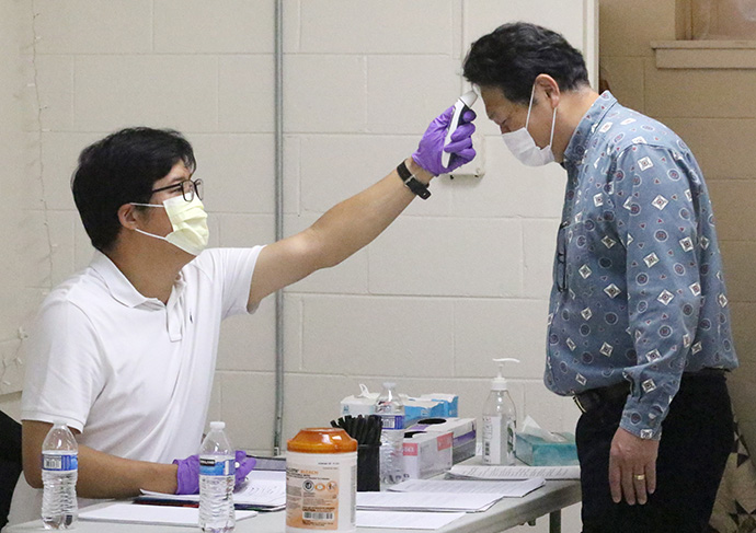 A member of the Healthy Church Team at Emmaus United Methodist Church checks the temperature of a member arriving to attend in-person service. Photo by the Rev. Thomas Kim, UM News.