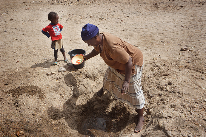 Brandina Chikango, 53, scoops water for her family from a shallow hole in the nearly dry bed of the Nyahuku River in Kotwa, Zimbabwe. Photo by Kudzai Chingwe, UM News.