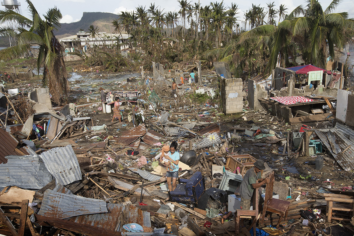 Sobreviventes do tufão Haiyan vasculham os destroços empilhados pela tempestade em Tacloban, Filipinas, em 2013, enquanto procuram seus pertences perdidos. Jovens metodistas de todo o mundo estão trabalhando juntos para combater o aquecimento global e têm se concentrado em equipar comunidades vulneráveis na linha de frente da mudança climática com os recursos de que precisam para se adaptar ao mundo em mudança. Foto de arquivo por Mike DuBose, UM News.