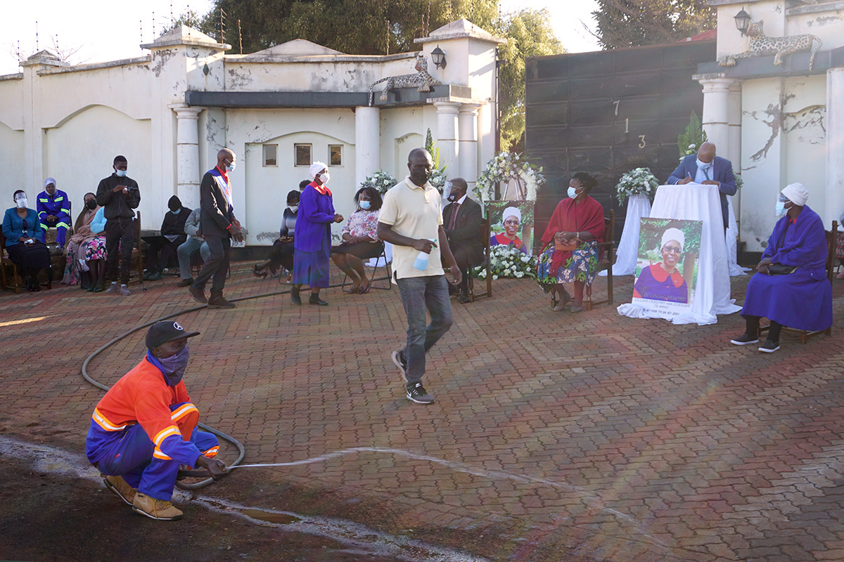 A few mourners gather outside the home of Lillian Chikomo in Harare, Zimbabwe, for her funeral. They sang softly while Simon Mafunda (center) helped make sure COVID-19 precautions were followed. Most people who would have attended the service in person paid their respects by driving by slowly in front of her home. Mafunda is lay leader of the Zimbabwe East Conference of The United Methodist Church. Photo by Kudzai Chingwe, UM News.