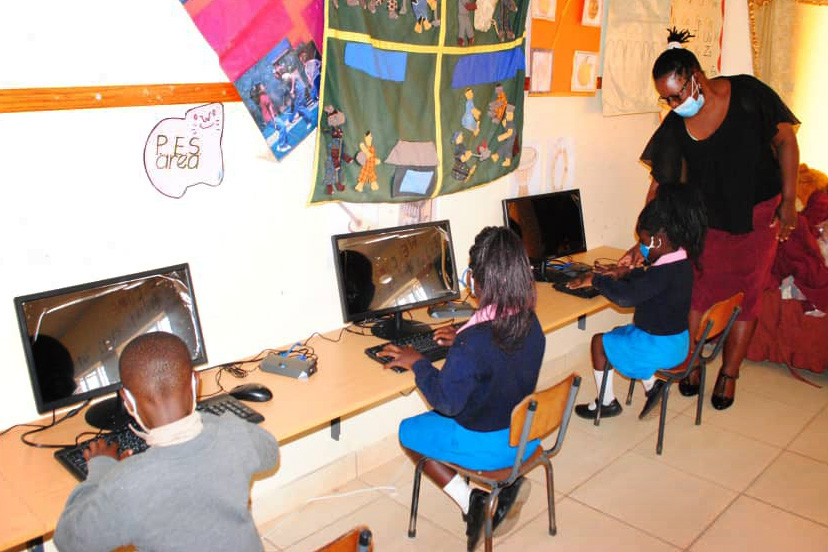 Early childhood teacher Ruth Nemakanga helps Patience Chipakatira learn to use a desktop computer at the United Methodist Hartzell Central Primary School in Mutare, Zimbabwe. A grant from the United Methodist Board of Global Ministries funded 10 desktop computers that will serve 173 students. Photo by Kudzai Chingwe, UM News.
