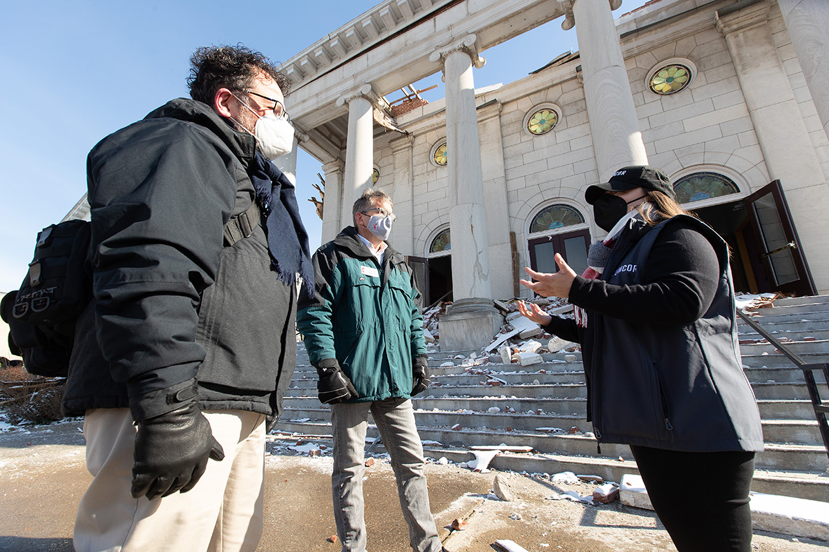 The Rev. Joey Reed (left) visits with Lara Martin of the United Methodist Committee on Relief (right) and the Rev. Rob Martin, assistant to Nashville Area Bishop William McAlilly, outside First United Methodist Church in Mayfield, Ky. Reed, the church’s pastor, took shelter in the church basement with his wife as the Dec. 10, 2021, storm approached because their parsonage does not have a basement. 
