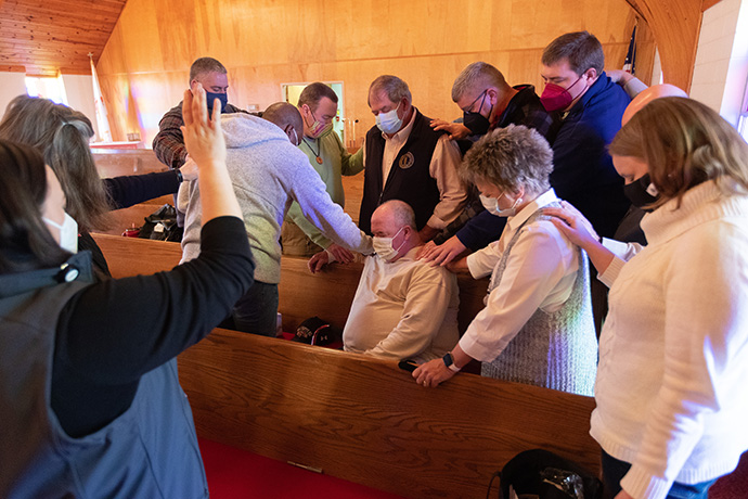 United Methodist Bishop Leonard Fairley (in gray sweatshirt) leads church leaders in prayer for Dawson Springs (Ky.) Mayor Chris Smiley (seated) and Hopkins County (Ky.) Magistrate Charlie Beshears during a meeting at Dawson Springs United Methodist Church to plan for recovery from a tornado that devastated the area. Photo by Mike Dubose, UM News.