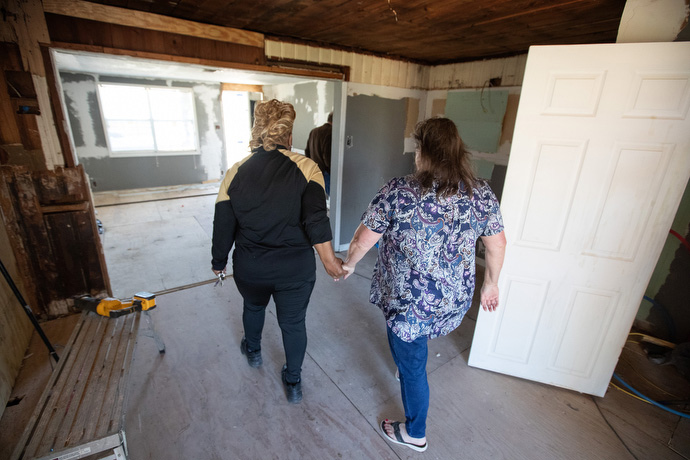 Debra Duhon (left) and Katherine Howell hold hands as they survey the progress of repairs to Duhon’s storm-damaged home in Lake Charles. Photo by Mike DuBose, UM News.