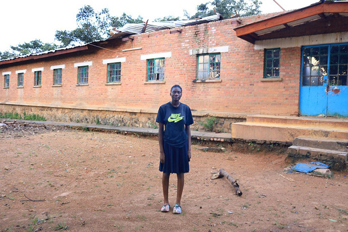 Kibambe Kazadi Gracia, a student at Mulungwishi Secondary School, stands in front of the girls' dormitory where part of the roof was blown off at Mulungwishi Mission, a United Methodist mission in the South Congo Episcopal Area. Photo by John Kaumba, UM News.