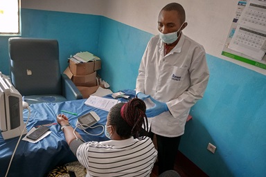 Le docteur Patrick Kilunji, directeur de la clinique Méthodiste Unie de Shungu à Kamina, en RDC, montre à une femme enceinte comment prendre sa propre tension artérielle à la clinique. En partenariat avec Harper Hill Global et d’autres organisations, la clinique et la Région épiscopale du Nord Katanga contribuent à éduquer les habitants des villages sur l’hypertension et les risques pour les femmes enceintes. Photo de la Rév. Betty Kazadi Musau, UM News.