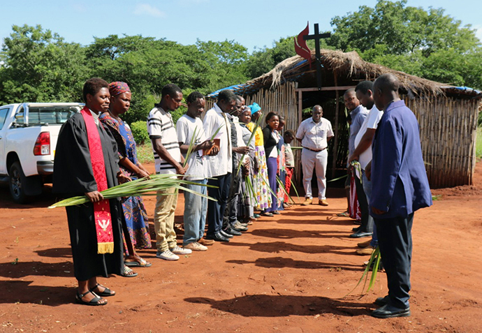 Members of Ninga United Methodist Church in the Cabo Delgado province, Mozambique, stand in prayer outside the church on Palm Sunday. District Superintendent Dercia Marrengula (left in red stole) joined the congregation for the service. Photo by Michaque Ali.