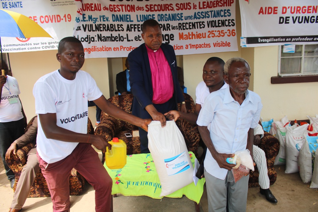 Le Bishop Daniel Lunge assisté des volontaires UMCOR dont Armand Osango et Placide remettaient le sac de riz à Papa Jean Okito l'une des victimes. L’Eglise a apporté de la nourriture à des personnes déplacées qui ont fui les affrontements entre deux communautés à la suite d’un conflit forestier. Photo par François Omanyondo, UM News.
