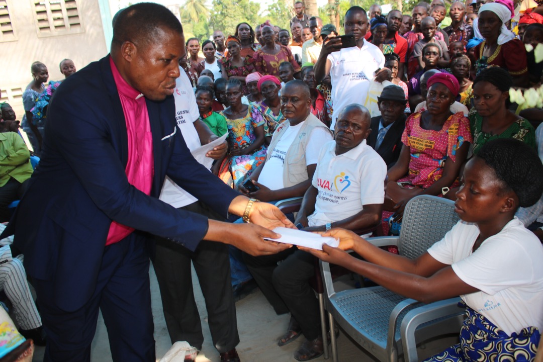 Bishop Daniel Lunge remet l'enveloppe d'assistance humanitaire à Mme. Christine Eseka Lokolo lors du lancement officiel de l'assistance humanitaire aux victimes du conflit entre Vunge et Nambelo Lohembe. Photo par François Omanyondo, UM News.