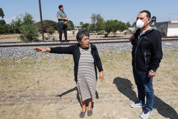 Virginia George-George shows the Rev. Arturo González Sandoval the railroad tracks behind her home in Tlaltelulco, Mexico, about 12 miles from Apizaco. She and her family found themselves with an unexpected ministry in caring for the migrants who rode freight trains headed north toward the United States. At rear is her pastor, the Rev. Uzi Castañeda Morales. Photo by Mike DuBose, UM News.