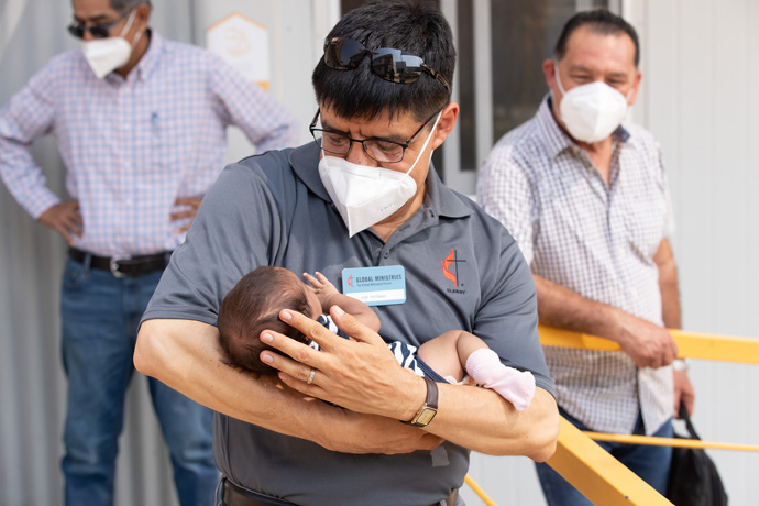 The Rev. Joel Hortiales cradles 11-day-old Dina at the Hospitalidad y Solidaridad migrant shelter in Tapachula. Dina was born as her family made its way north from El Salvador. Hortiales, a United Methodist missionary who serves as director of Hispanic/Latino ministries and border concerns for the California-Pacific Conference, was part of a group of leaders from the Methodist Church of Mexico and The United Methodist Church who traveled to southern and central Mexico to learn more about migration-related ministries there. Photo by Mike DuBose, UM News.