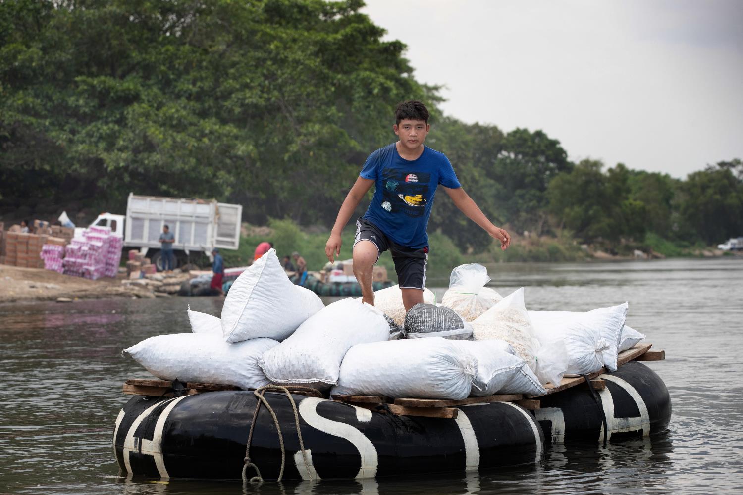Un niño usa una balsa hecha con carcasas de llantas amarradas a tablones de madera para transportar mercancías a través del río Suchiate desde Ciudad Hidalgo en México hasta las cercanías de Ciudad Tecún Umán en Guatemala. Foto de Mike DuBose, Noticias MU.