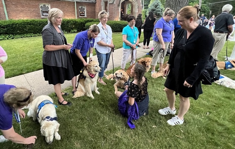 Perros entrenados ayudan a brindar consuelo a las personas que luchan el dolor por lo ocurrido fuera de la vigilia de oración en la Iglesia Presbiteriana de Highland Park. Foto cortesía de la Conferencia Anual del Norte de Illinois.